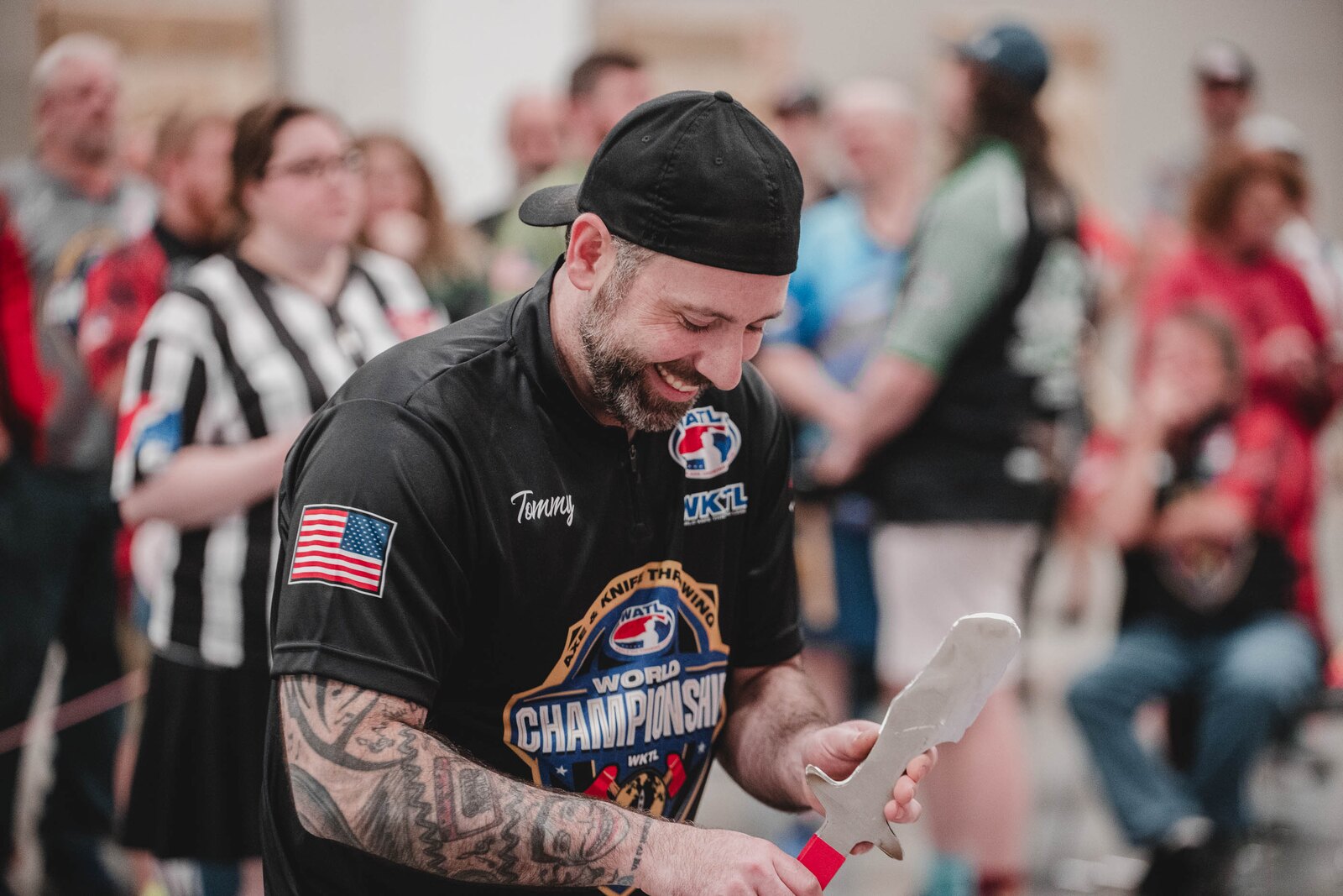 A smiling WKTL competitor inspecting a throwing knife at an event