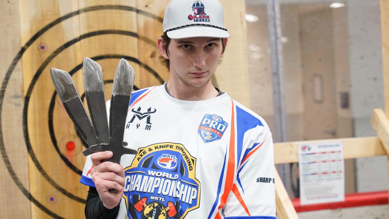A WKTL World Championship competitor holding three competition knives at the lane